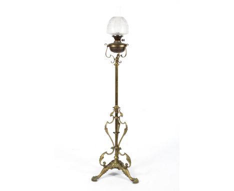 A brass oil lamp. With etched floral shade and chimney on brass burner marked British Made, on studded scroll support issuing
