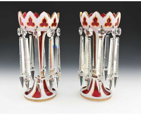 A pair of 19th century Bohemian cased glass lustre candlesticks, white opaque over ruby with gilt bordered panels and trefoil