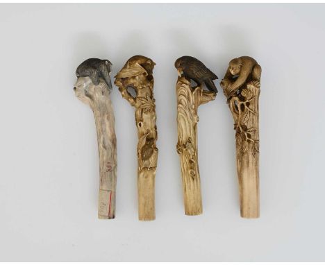 Four Japanese carved bone handles, Meiji, each terminal modelled in high relief with a different animal atop a branch, peerin