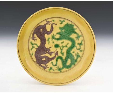 A Chinese famille jaune dish, Kangxi mark, yellow ground saucer form, incised with dragons and pearl, glazed in green and bro