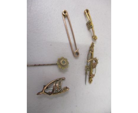 A 9ct gold coloured metal jewellery to include a stick pin and four brooches 