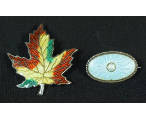 A sterling silver and enamel leaf brooch; silver and enamel oval brooch