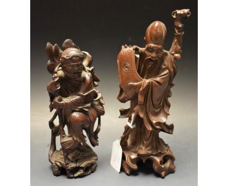 A 19th century Chinese hardwood carving, of Shou Lao, the elderly sage unfolds a scroll of wisdom, wearing flowing robes, his