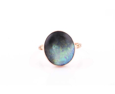 A yellow metal and boulder opal ring, the rounded oval stone in a closed-back setting, with shaped shank, unmarked (tests as 