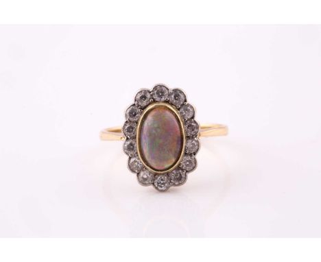 An opal and diamond cluster ring, opal cabochon measuring 8.5 x 5.9mm, white millegrain set surround of fourteen round cut di