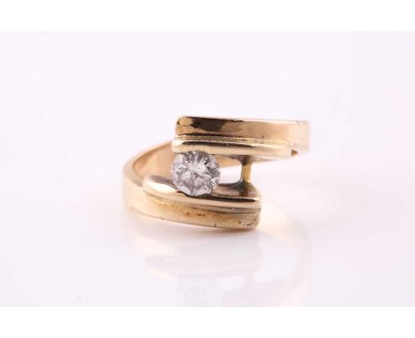 A single stone diamond ring; the round brilliant cut diamond in a crossover tension set yellow metal mount. (unmarked) Diamon