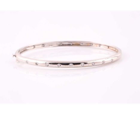 A diamond set bangle; the centre with nine flush set round brilliant cut diamonds along a curved and polished band. Hinged, w