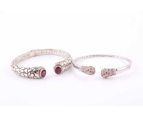 A silver torque bangle, with a mixed oval-cut ruby set to each terminal within a rope-twist yellow metal border, hinged openi