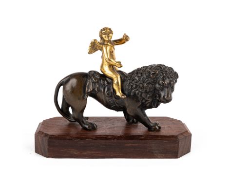 Of a putti astride a lion standing loose on an associated wooden base.12cm wide x 10cm highThe collection of Paul Whitfield (