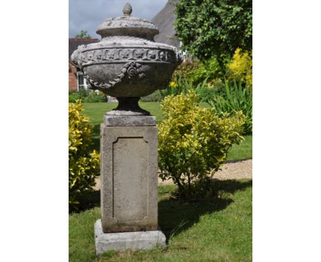 The cast reconstituted stone squat urn with lion mask decoration and husk swags, mounted on a panelled plinth base.The urn 49