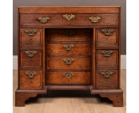 With a caddy top above a cross banded inlaid frieze. The long drawer above a recess containing four drawers on an adjustable 