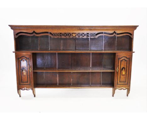 An early 19th century oak dresser rack, with a moulded dentil cornice above three shelves flanked by a pair of spice cupboard