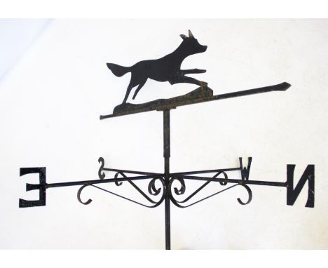 A wrought iron running fox weather vane, the rotating running fox pointer above the N,E,S,W indicators upon a wall fixing bra