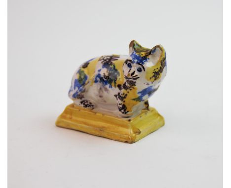 A 20th century faience cat novelty inkwell, decorated in a blue, yellow and brown sponge glaze, to a yellow  plinth, unmarked