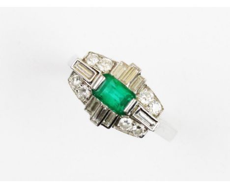 A diamond and emerald 18ct white gold cluster ring, the oblong shaped head comprising a rectangular step cut emerald claw set