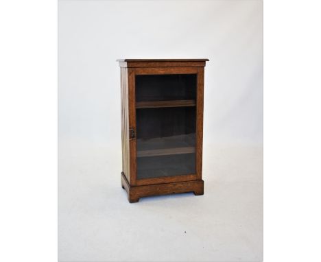 An Edwardian oak music cabinet, the rectangular moulded top above a single glazed door, enclosing two sliding trays, raised u