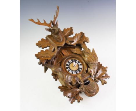 A mid 20th century West German carved oak cuckoo clock, the case applied with a carved stags mask, figure of a rabbit and the