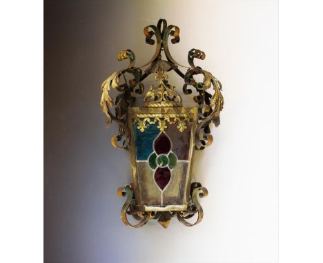 An early 20th century wrought iron hanging lantern, of tapering form with four leaded and coloured glass panels, 55cm 