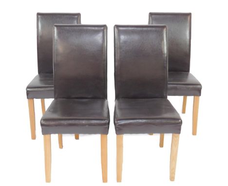 A set of four light oak single dining chairs, with dark brown leather backs and over stuffed seats, raised on tapering square
