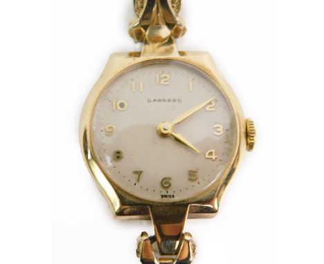 A Garrard 9ct gold cased lady's wristwatch, circular white dial bearing Arabic numerals on a plated strap.