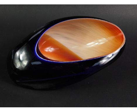 A late 20thC blue studio glass bowl, of shell form, decorated internally in orange and cream, etched signature, 23cm long. 