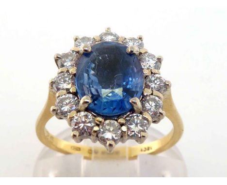 A 18 carat gold, sapphire and diamond cluster ring, the central oval cut stone 9.9 x 8 x 4.4mm, in a surround of brilliants t