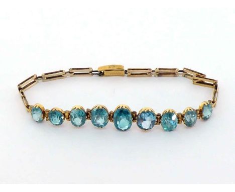 A 1940s gold and blue zircon line bracelet, composed of nine graduated oval cut stones (one replaced with a blue topaz), exte