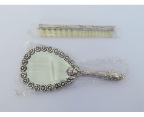 A Portuguese silver handmirror and silver-backed comb, .935 standard, the ovoid mirror with border of flower-heads and with b