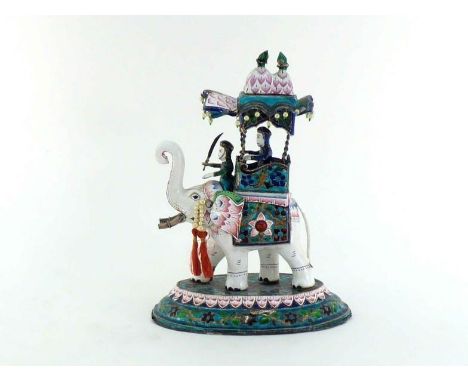 An Indian  painted enamel model of a richly caparisoned white elephant with mahout and howdah carrying a dignitary, all on an