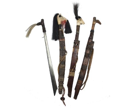 Four Malayan swords (mandau or parang ilang), the first with 20.5 inch blade of symmetrical-section forged with fine scrollin