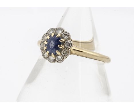 A sapphire and diamond cluster ring, the oval mixed cut sapphire heavily abraded, in claw setting flanked by brilliant cut di