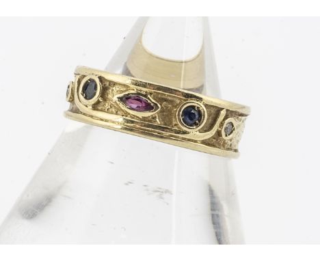 A continental yellow metal 750 marked sapphire, ruby and diamond ring, the textured band with colette set gems, ring size M, 