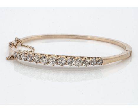A French early 20th Century diamond set hinged bangle, the old cut claw set diamonds all in yellow gold on a pierced gallery 