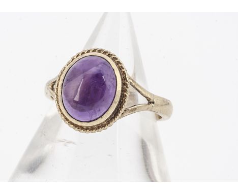 An amethyst cabochon 9ct gold dress ring, the mauve stone with rope twist setting, yellow gold shank, unmarked, ring size N, 