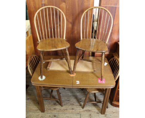 An oak rectangular extending dining table with four stick back chairs 