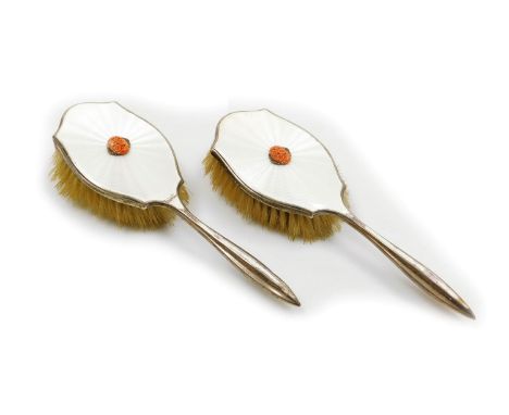 A pair of George V silver and white guilloche enamel hairbrushes, with engine turned decoration, set centrally with a coral a