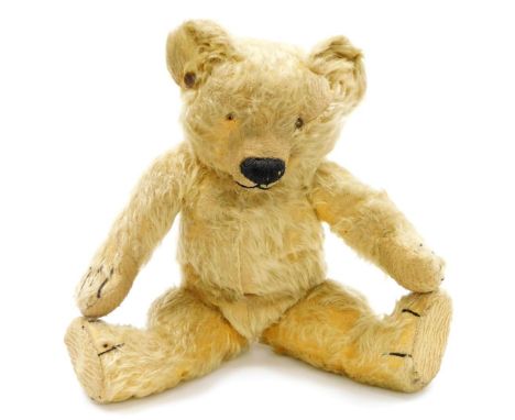 An early 20thC vintage Teddy bear, with a humped back, centre stitched body, jointed arms, legs and head, the snout stitched,