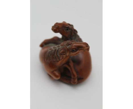 A JAPANESE CARVED WOOD NETSUKE OF TWO HORSES, 3.5cm high 