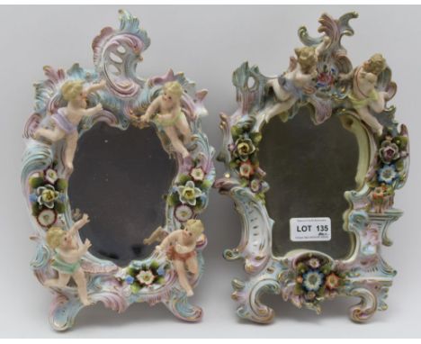 A PAIR OF SITZENDORF PORCELAIN WALL MIRRORS, scroll fork frames, floral encrusted and cherub mounted, gilded and polychrome, 