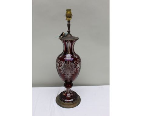 AN EARLY 20TH CENTURY RED FLASH OVERLAY GLASS BODIED TABLE LAMP with cut panels &amp; floral etched swags, metal mounted, 40c