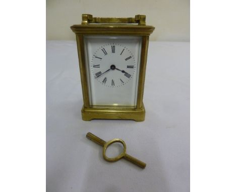 An eight day brass carriage clock, the white enamel dial with Roman numerals and key
