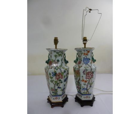 A pair of Chinese style porcelain lamp bases on hardwood stands