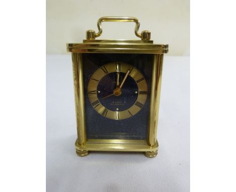 A miniature Dunhill 8 day carriage clock with Roman numerals and swing handle on four bun feet