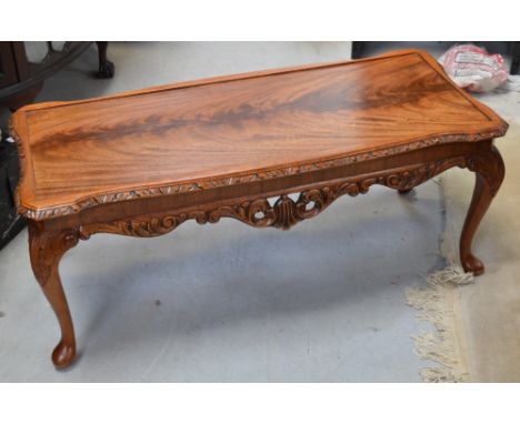 A modern light oak coffee table with carved knees on cabriole legs.