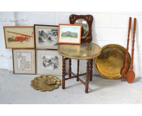 A collapsible wooden brass topped table, a decorative wall mirror, brass trays, prints, an oversized spoon and fork.