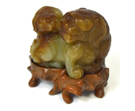 A Chinese carved celadon and russet jade group of a Dog of Fo with pup, mounted on a shaped rosewood stand, width approx 8cm.