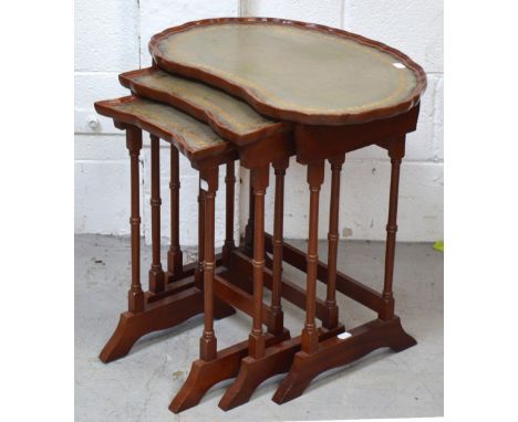 A mahogany kidney shaped nest of leather topped tables on turned legs and bracket feet.