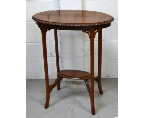 An Edwardian oval walnut side table with lower shelf supported by carved fretwork on splayed tapering legs, 40 x 66cm.