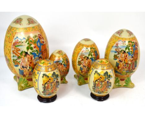 A set of six Japanese transfer ware and hand painted ornamental eggs of various sizes on shaped ceramic plinths (6).