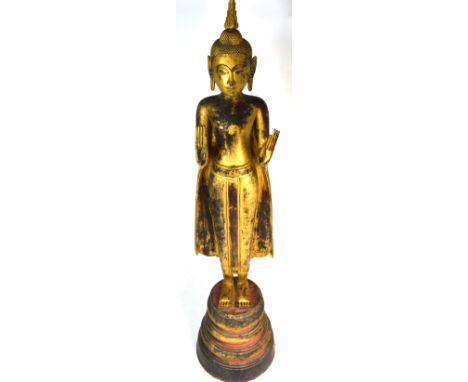 A large 19th century Chinese carved wood and gilded standing figure of Shakyamuni wearing a cloak with hands raised to the fo